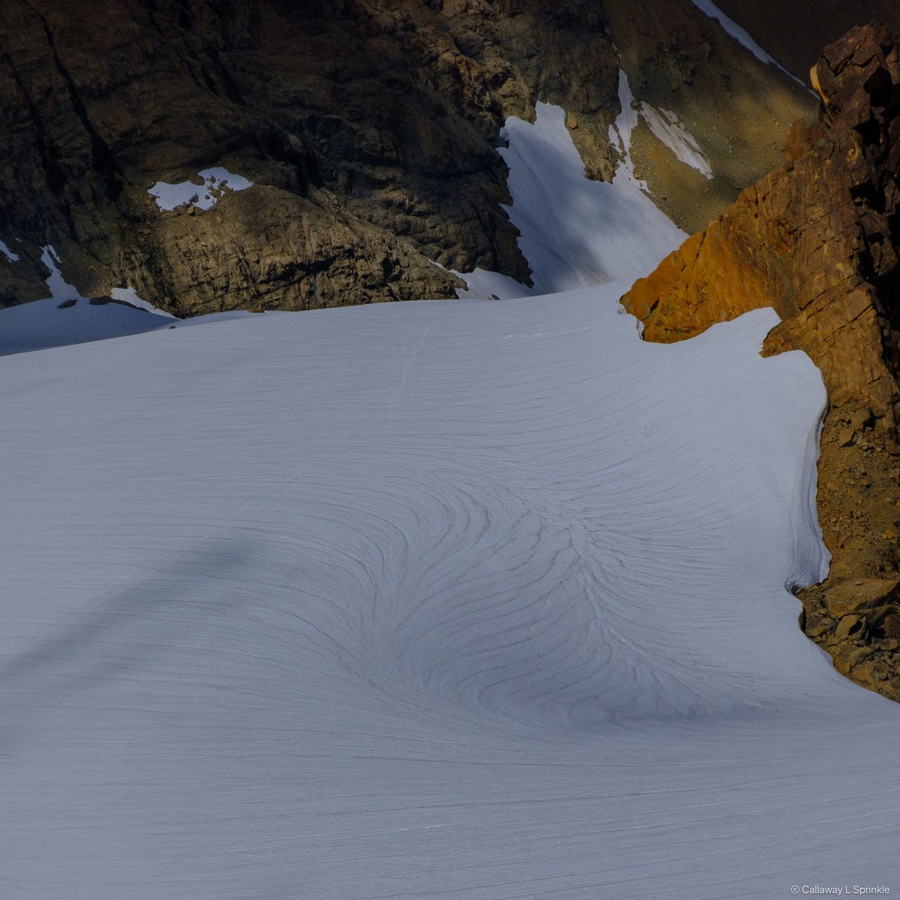 Sun-cupped glacier surface in raking light, an abstract field of scalloped snow